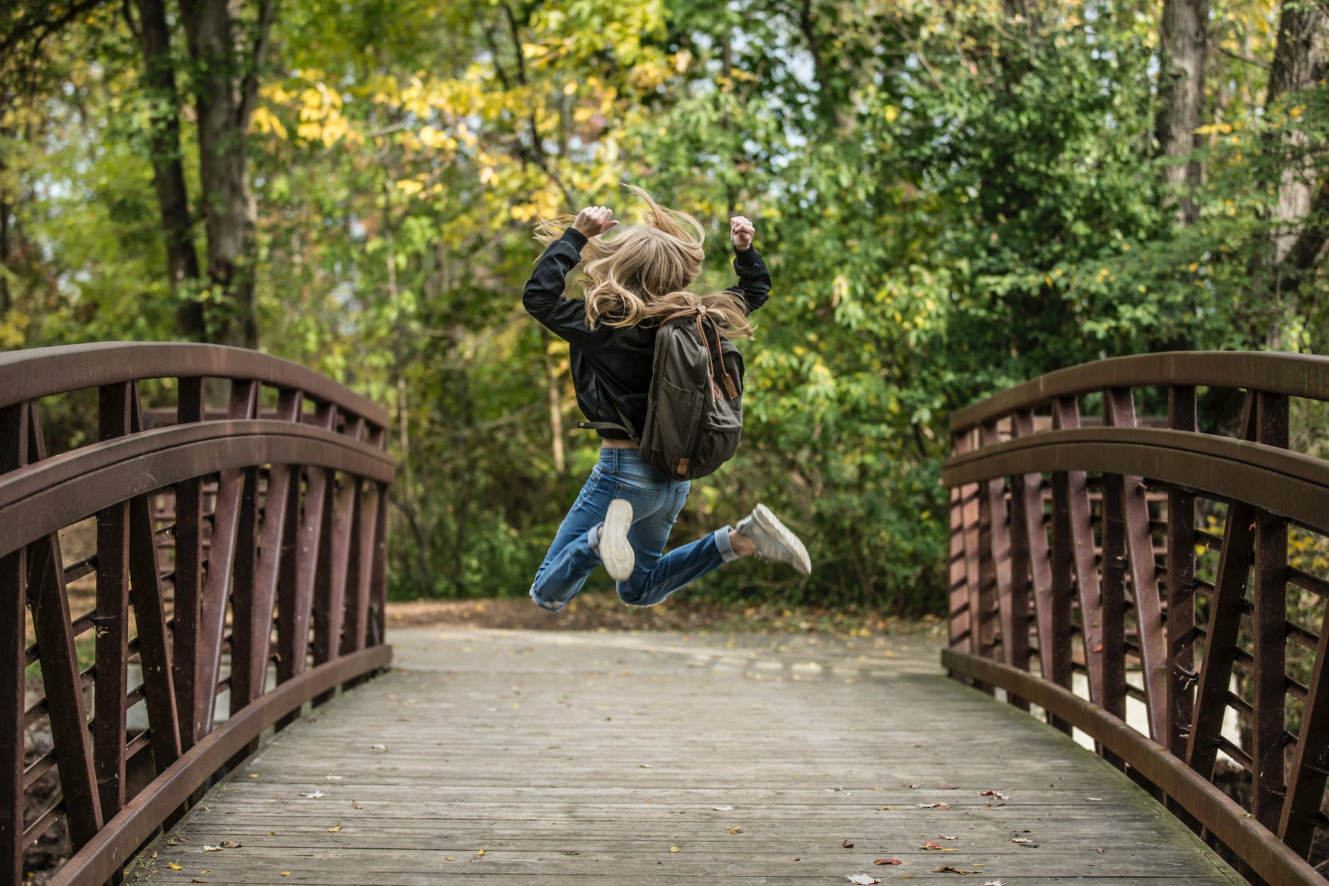 girl jumping on the bridge wearing black jacket